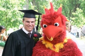 student in mortarboard standing with phoenix mascot